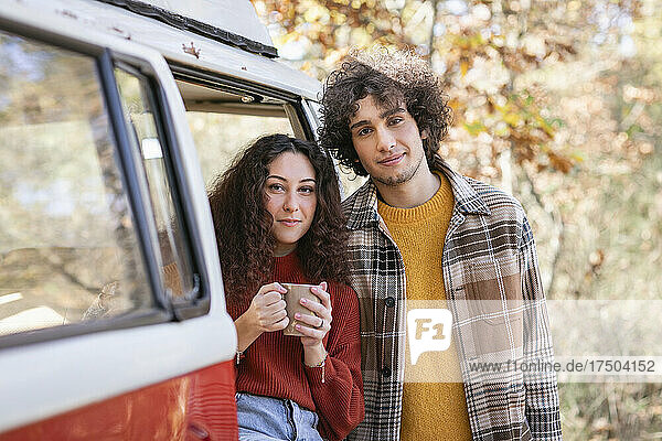 Young couple at campervan in autumn forest
