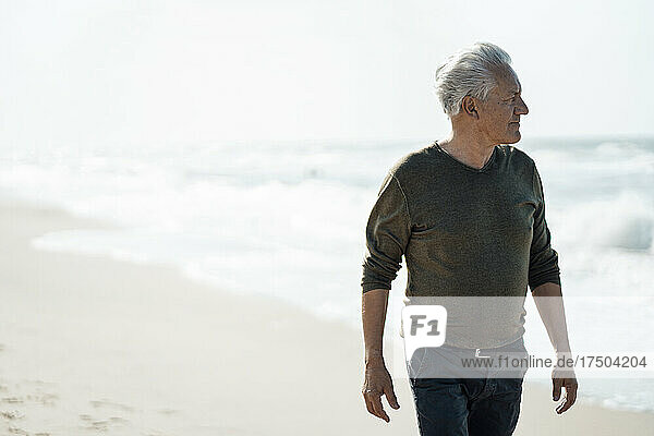 Älterer Mann geht am Strand spazieren