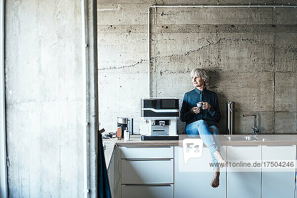 Thoughtful businesswoman with coffee cup sitting at cafeteria