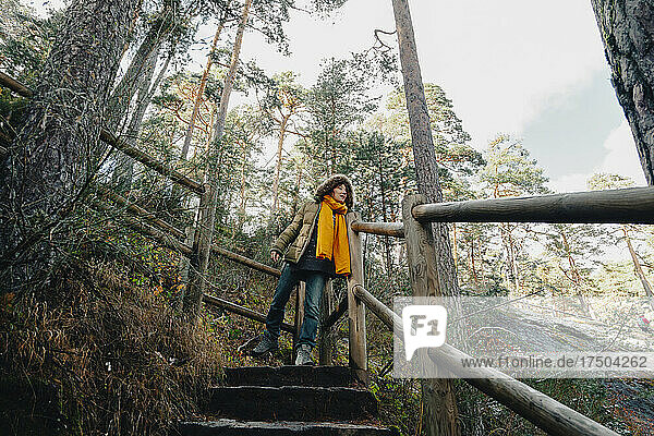Woman in coat moving down on steps in forest