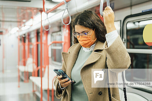 Curvy woman using mobile phone in train during pandemic