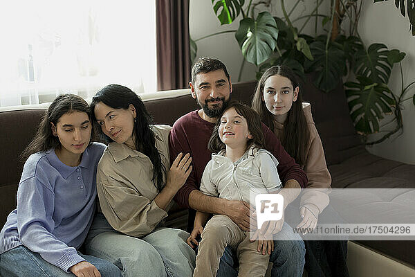 Lächelnde Familie sitzt zu Hause zusammen auf dem Sofa