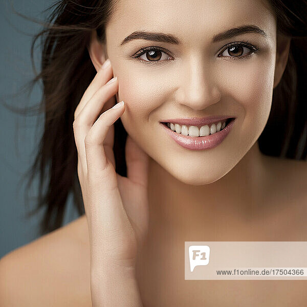 Smiling young woman touching flawless skin