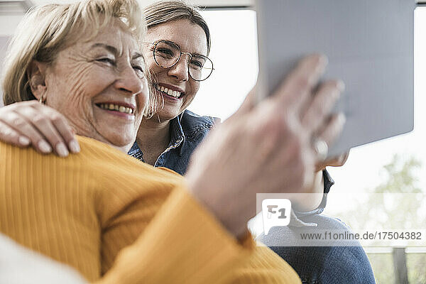 Smiling women using tablet PC at home