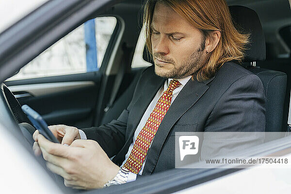 Businessman using mobile phone in car
