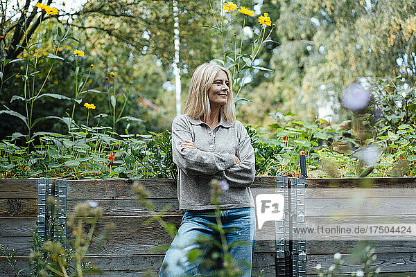 Smiling woman with arms crossed at garden