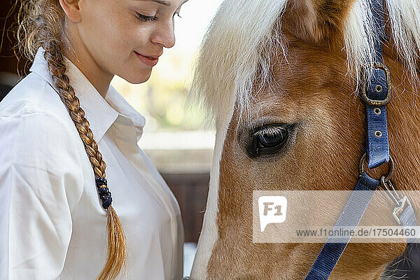 Redhead woman looking at horse in stable