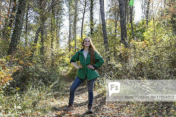 Young woman with hand on hip standing in forest