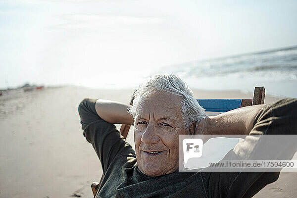 Smiling man relaxing on chair at beach