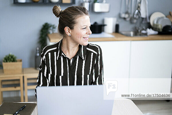 Thoughtful businesswoman with laptop at home