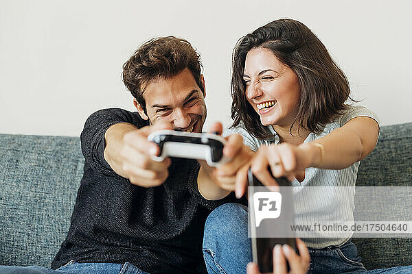 Happy young man and woman playing with game controller at home