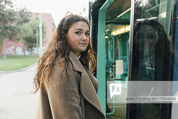 Smiling woman in overcoat standing near cable car