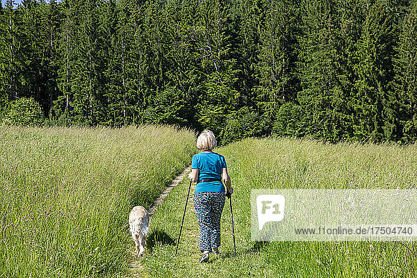 Woman with Golden Retriever hiking on grass