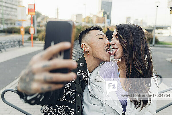 Liebevolles Paar  das Zungen berührt und ein Selfie mit dem Smartphone macht