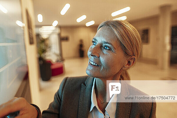 Smiling businesswoman looking at screen in office