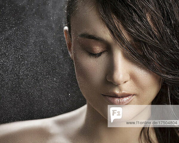 Water spraying on beautiful woman with eyes closed