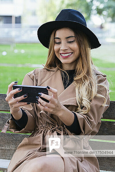 Smiling woman watching mobile phone on bench