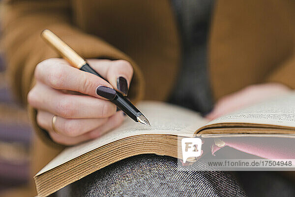 Woman with fountain pen writing in book in park