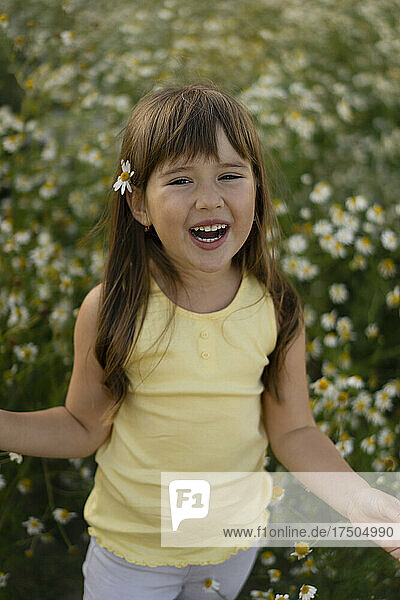 Playful girl wearing flower in meadow