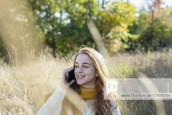 Happy woman talking on smart phone on sunny day