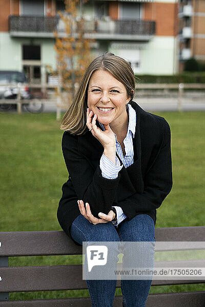 Smiling woman sitting on top of park bench