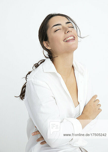 Smiling woman with eyes closed against white background