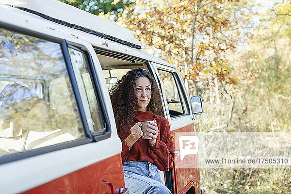 Young woman having coffee in compervan