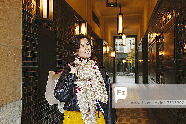 Smiling woman holding shopping bags at corridor