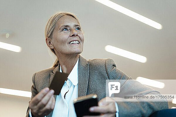 Businesswoman with credit card and mobile phone in office