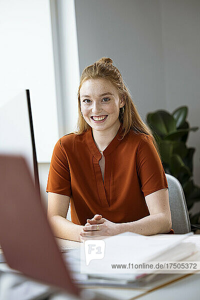 Lächelnde Geschäftsfrau  die am Schreibtisch sitzt