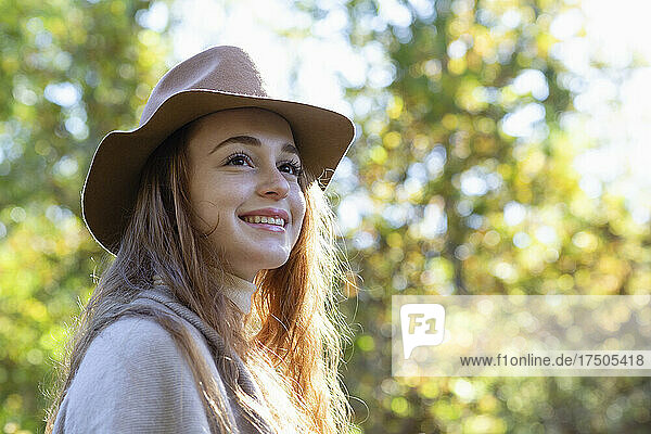 Lächelnde  nachdenkliche Frau mit Hut im Wald