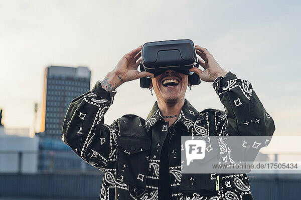 Happy man enjoying wearing virtual reality headset in city