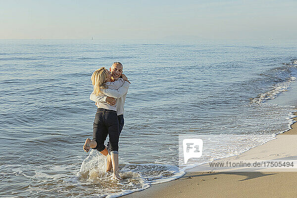 Mann spielt mit Frau im Wasser am Strand