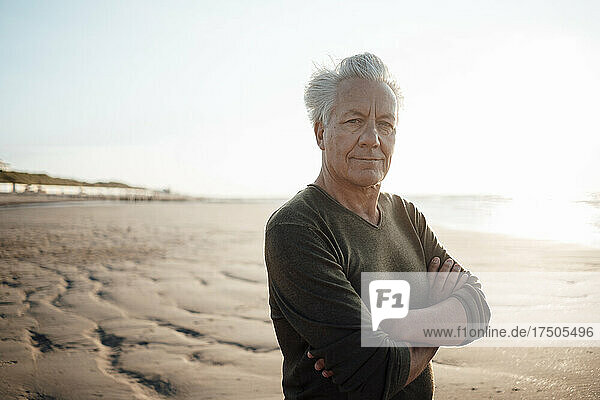 Man standing with arms crossed at beach