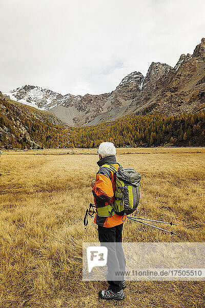 Tourist mit Rucksack blickt am Wochenende auf die Berge in den Rätischen Alpen  Italien