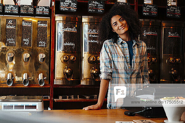 Smiling owner standing at cash register in coffee roastery