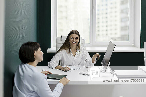 Smiling saleswoman gesturing looking at client in office