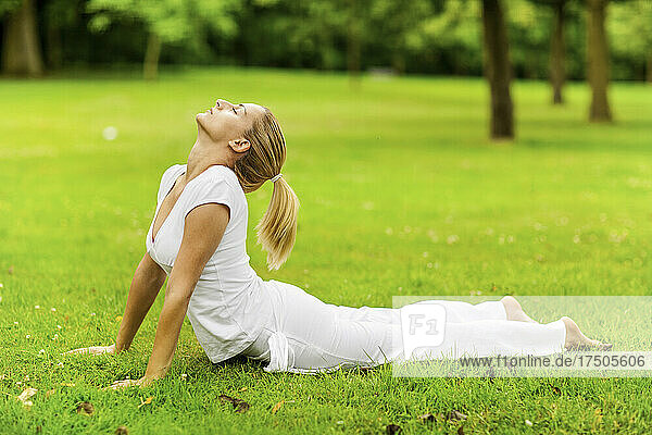 Junge flexible Frau übt Kobra-Pose im Park