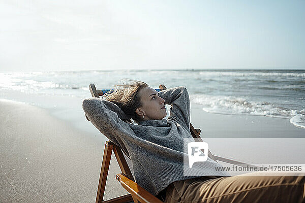 Junge Frau entspannt sich auf einem Stuhl am Strand