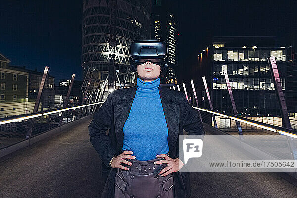 Businesswoman using virtual reality headset standing on bridge in city