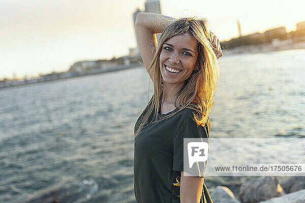 Lächelnde Frau mit der Hand im Haar am Strand von Bogatell  Barcelona  ??Katalonien  Spanien