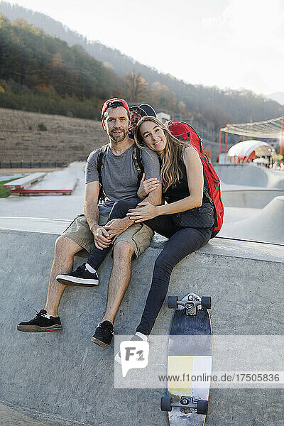 Woman sitting with man on wall at skatepark