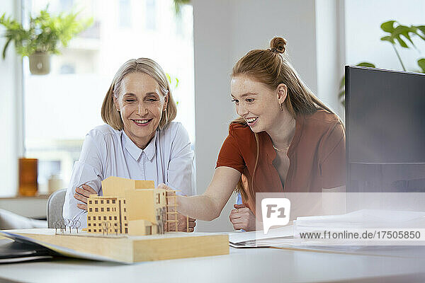 Female architect discussing with colleague over model in office