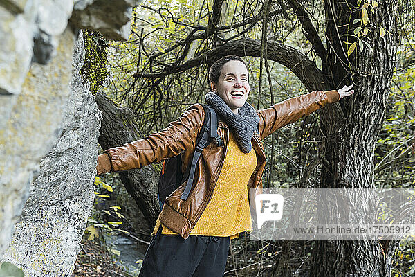 Happy woman with arms outstretched hiking in forest