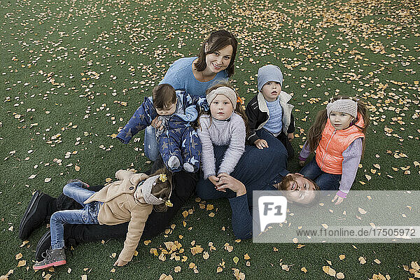 Family sitting together on lawn covered with autumn leaves