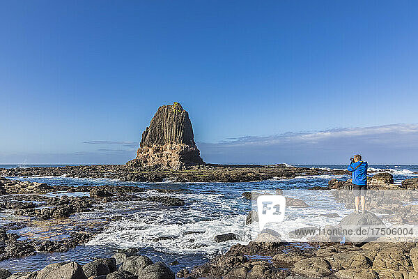 Australia  Victoria  Cape Schanck  Male tourist photographing Pulpit Rock