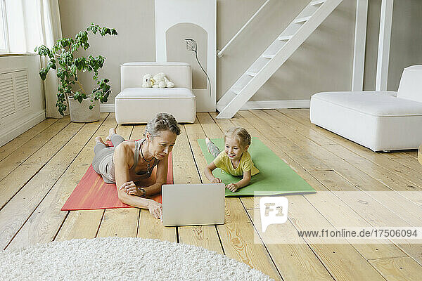 Mother and daughter learning yoga through laptop at home
