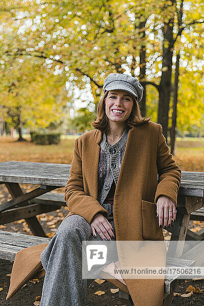 Smiling woman sitting on bench in autumn park