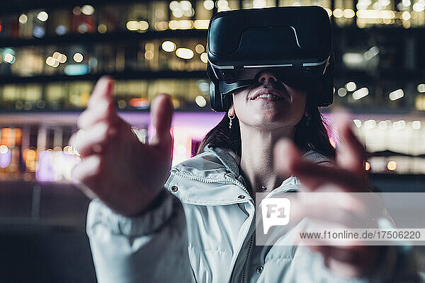 Woman in virtual reality headset gesturing at night