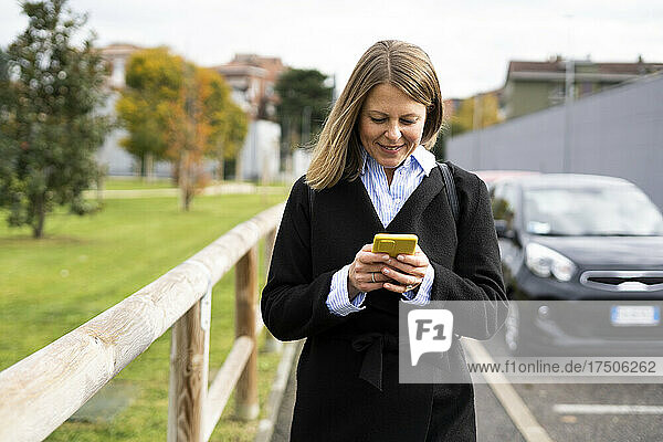 Woman using mobile phone on road